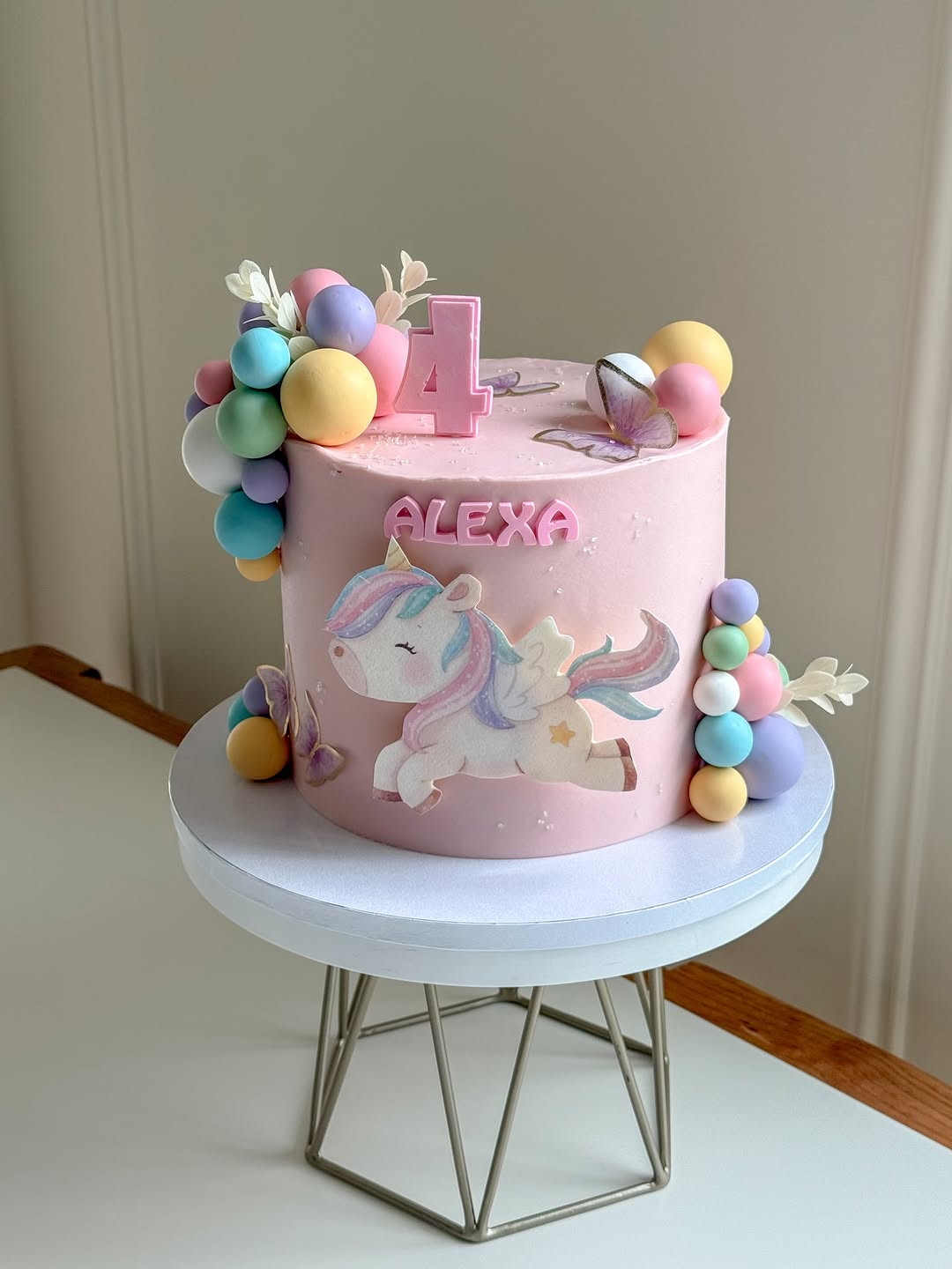pink unicorn birthday cake with balloons for a 4th birthday